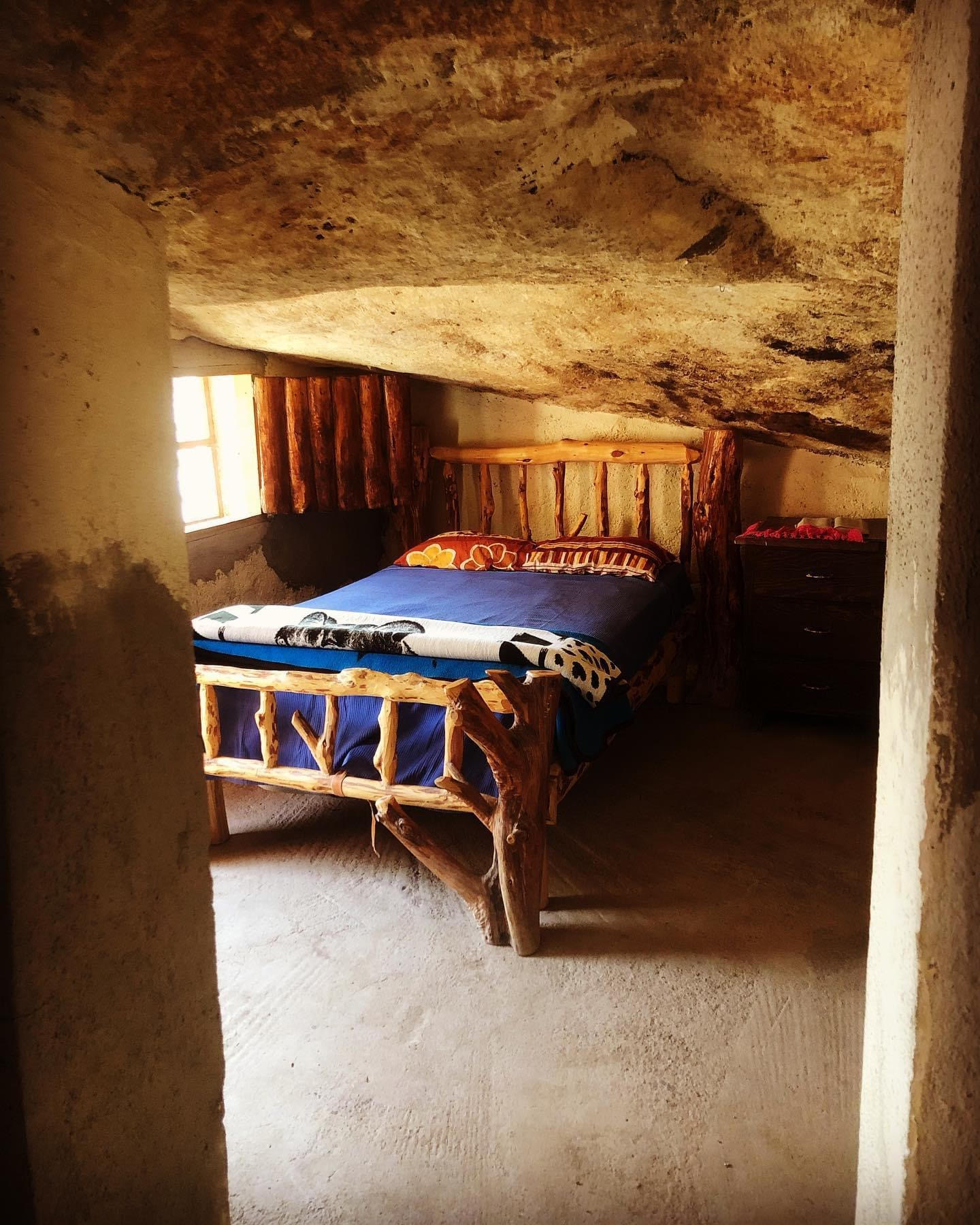 Sleeping quarters at Casa Piedra. A rustic bed covered with a bright blue blanket.